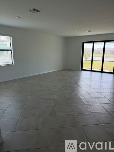 A large empty room with tiled flooring and a view of the outside through the windows.
