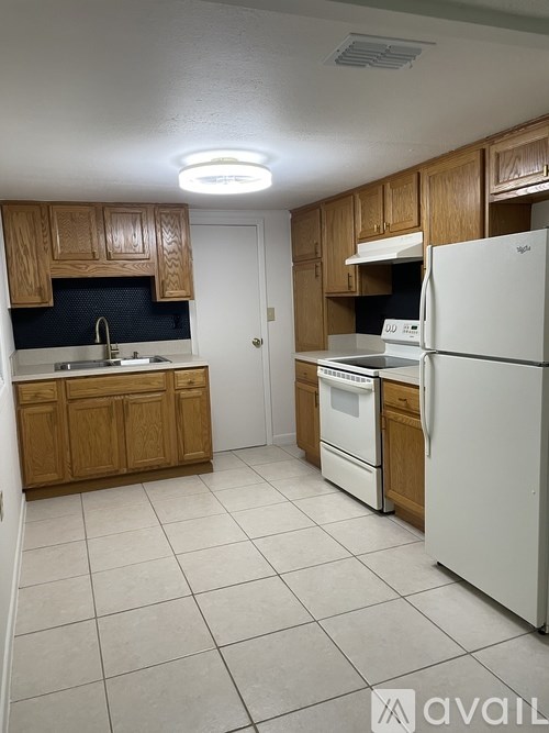 A kitchen with white appliances and wooden cabinets.
