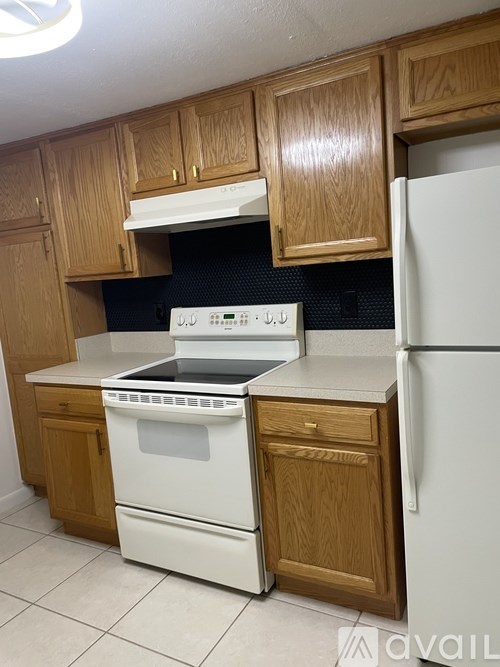 A kitchen with wooden cabinets and a white fridge.
