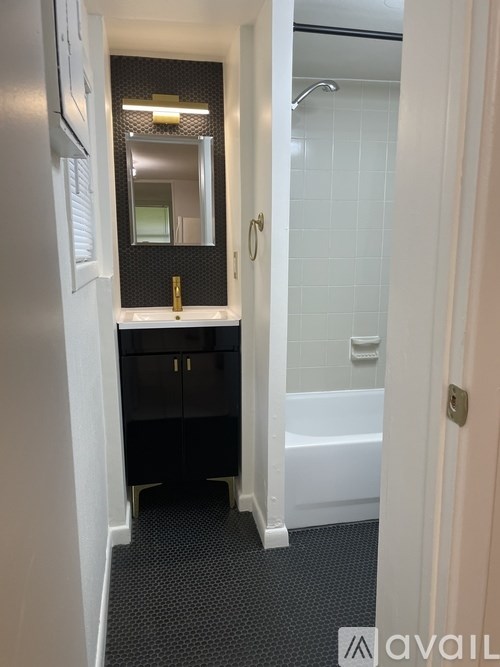 A bathroom with a white tub and black cabinets.