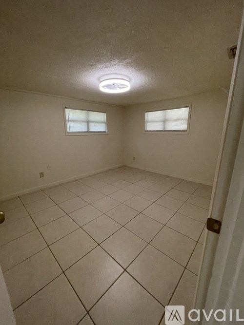 A room with white tiled flooring and two windows.