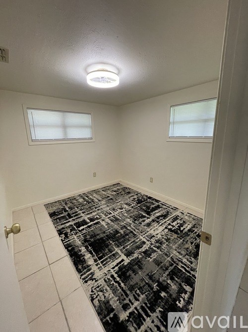 A room with a black and white tiled floor and two windows.