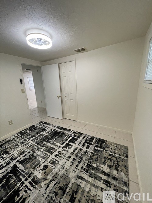 A room with a rug on the floor and a ceiling light.