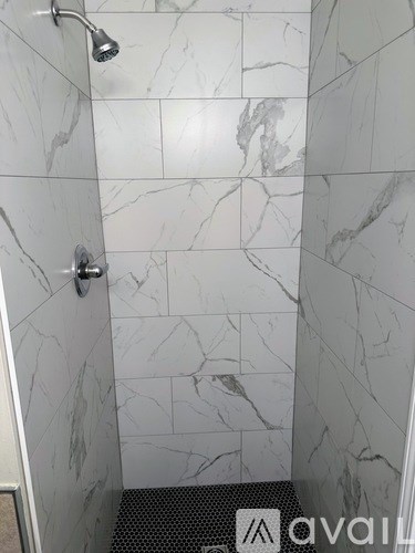 A marble tiled shower with a drain in the middle.