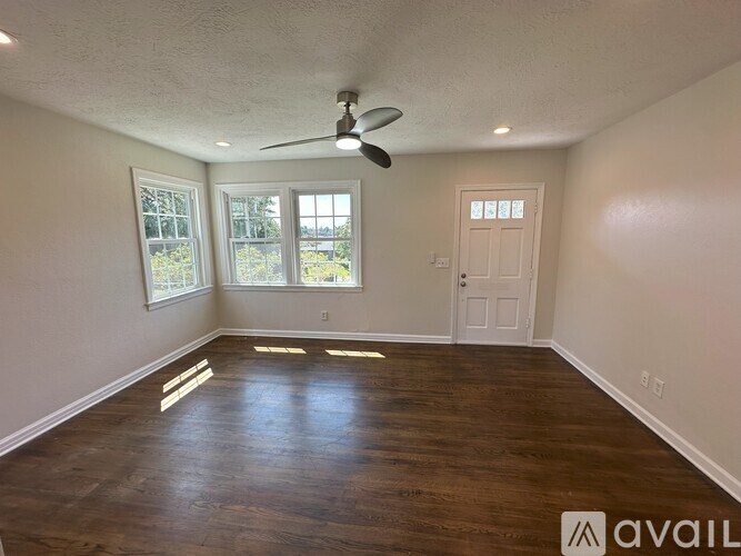 A room with a ceiling fan and wooden flooring.