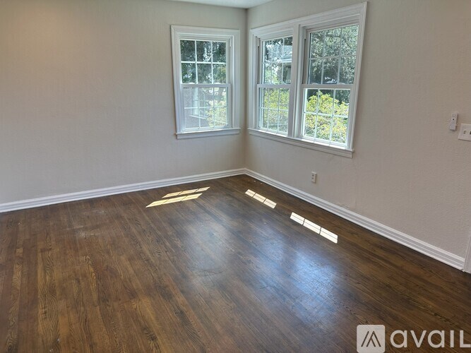 A room with wooden floors and two windows.
