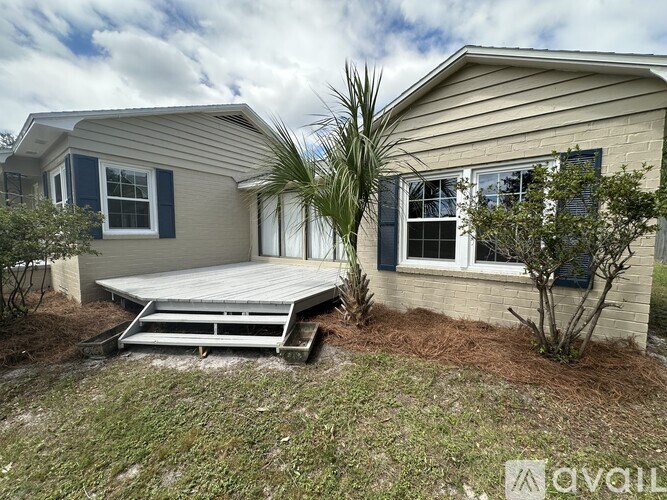 A house with a deck and a palm tree in front.