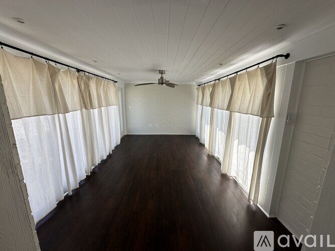 A spacious room with wooden floors and white walls.