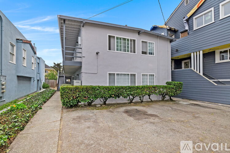 A grey house with a small front yard and a sidewalk.