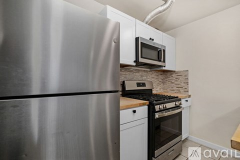 A kitchen with a stainless steel refrigerator and a microwave above the stove.