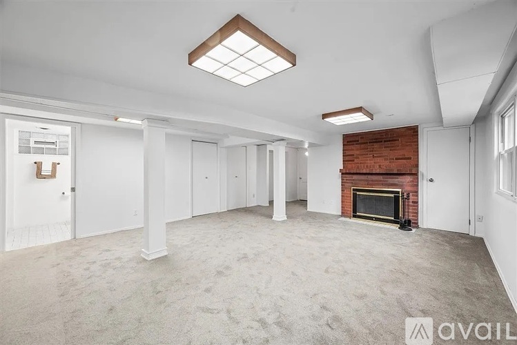 A spacious living room with a fireplace and a skylight.