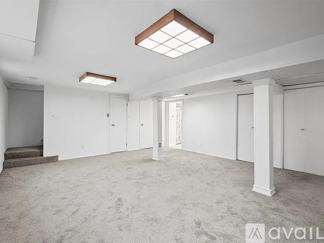 A spacious, empty room with white walls and carpeted floor.