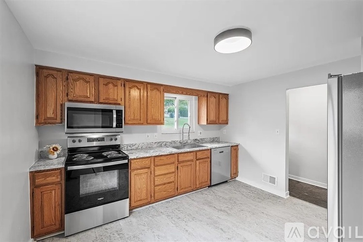 A kitchen with wooden cabinets and a stainless steel refrigerator.