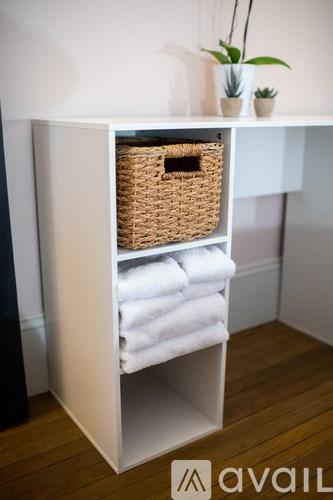 A white towel rack with a basket on top of it.