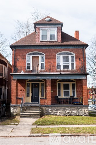 A red brick house with a black door and a small porch.