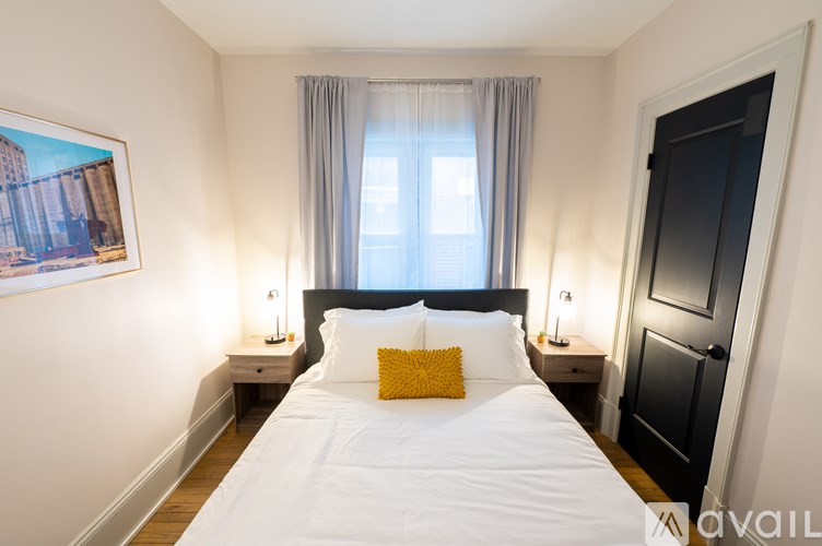 A bedroom with a large bed, two nightstands, and a window with curtains.