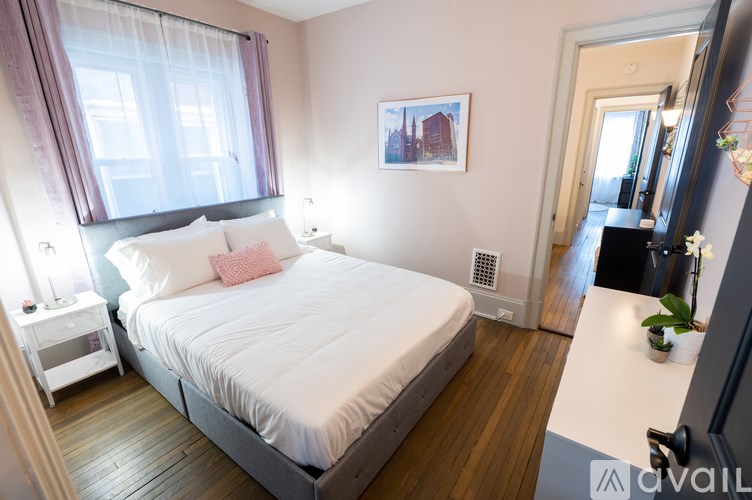 A bedroom with a large bed and a window with curtains.