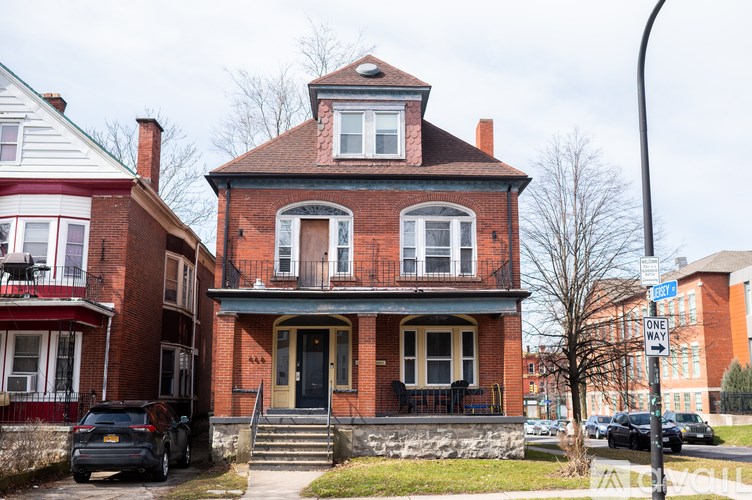A red brick house with a black door and a sign that says one way.