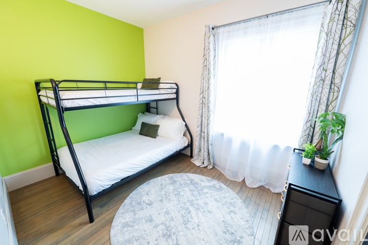 A room with a bunk bed and a window with curtains.