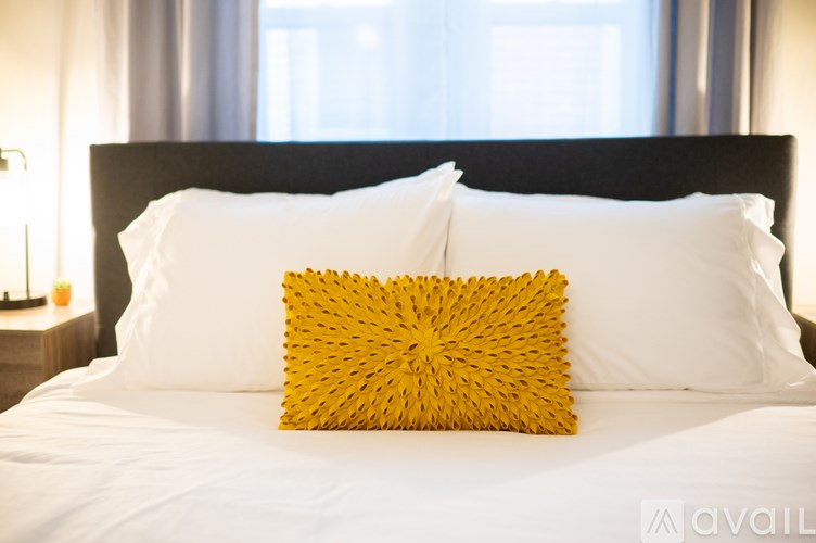 A bed with a white sheet and a yellow pillow.