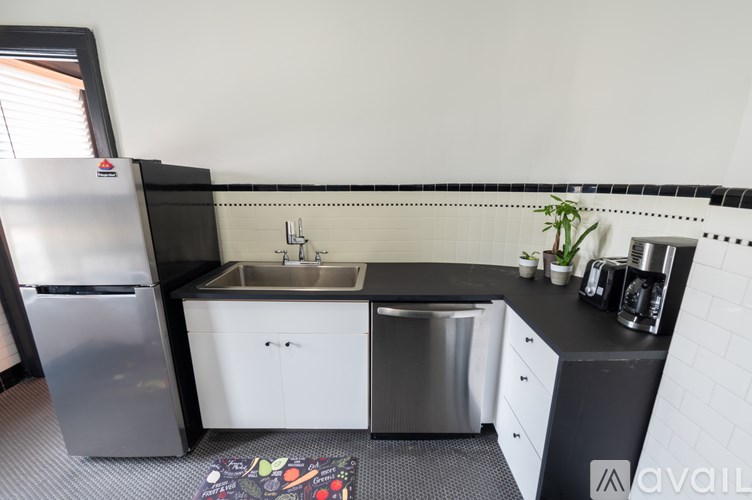 A modern kitchen with a stainless steel refrigerator, a white sink, and a black countertop.