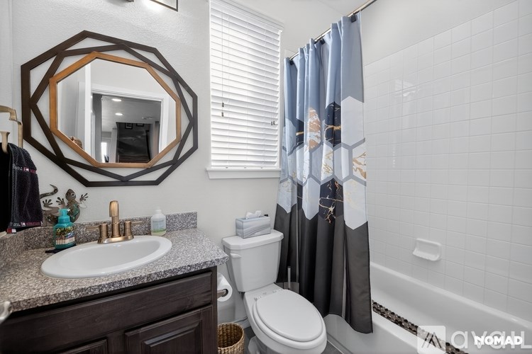 A bathroom with a white sink and a mirror with a wooden frame.