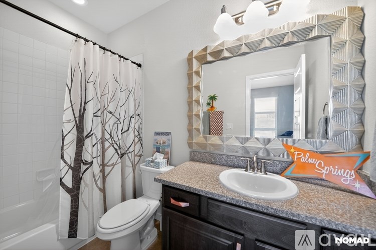 A bathroom with a toilet, sink, and a mirror.
