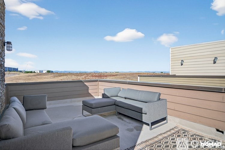 A grey couch and ottoman are on a patio with a view of the desert.