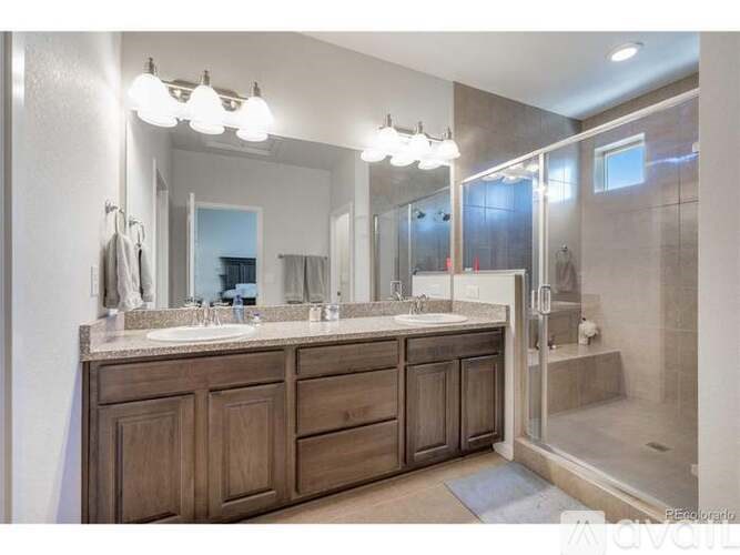 A bathroom with a large mirror, double sinks, and wooden cabinets.