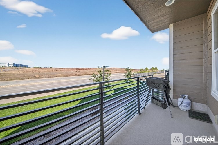 A balcony with a black railing and a chair.