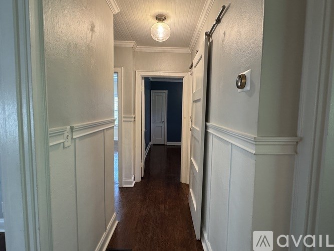 A long hallway with white walls and wood floors.