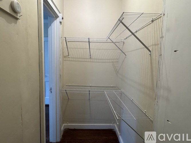 A white wall with a door and a metal shelf.