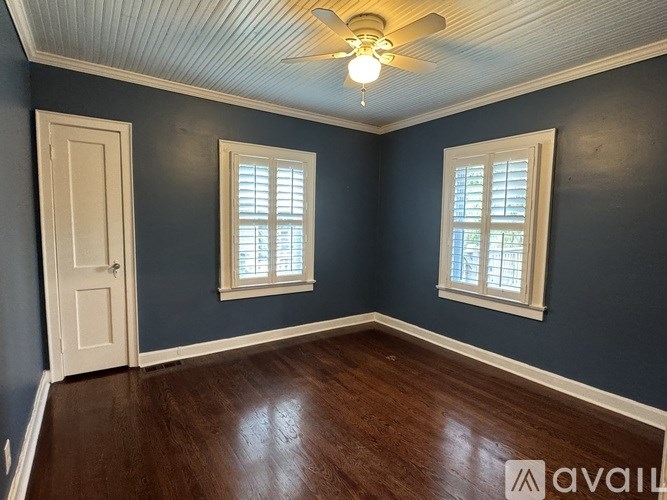 A room with a ceiling fan and two windows.