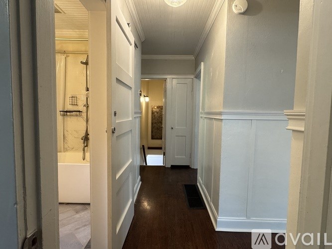 A hallway with white walls and a wooden floor.