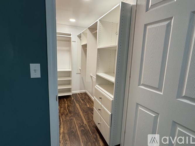 A hallway with a white door and a light switch on the wall.