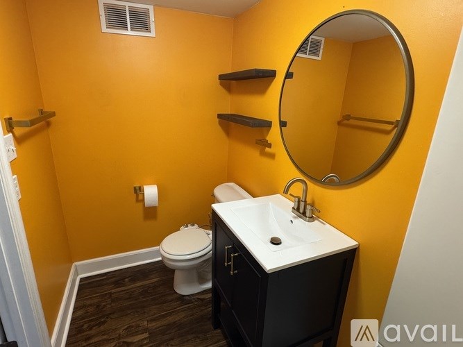 A bathroom with a toilet, sink, and mirror.
