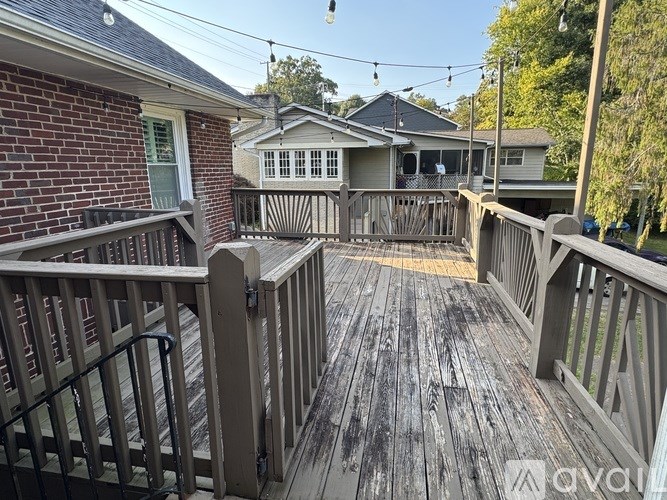 A wooden deck with a railing and a house in the background.