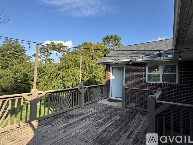 A wooden deck with a railing and a house in the background.