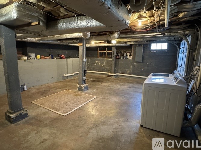 A large, empty basement with a concrete floor and exposed pipes.