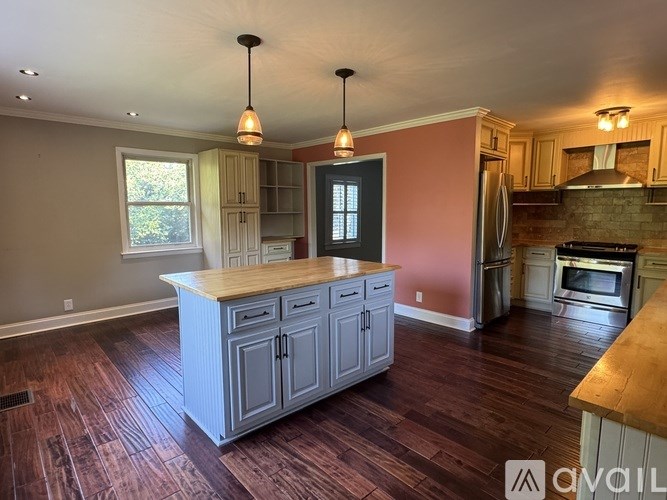 A kitchen with a wooden island and pendant lights.