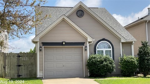 A house with a grey garage door and a window above it.