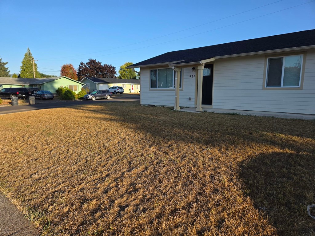 A house with a white siding and a black door is in the foreground of the image.