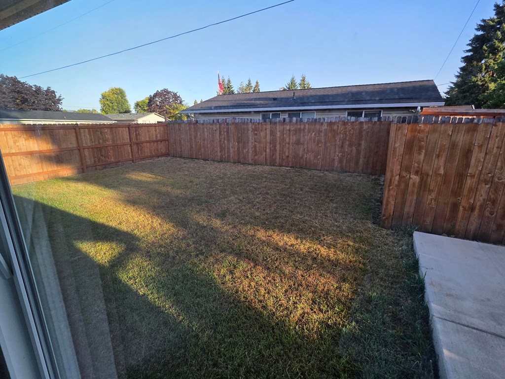 A backyard with a wooden fence and a grassy area.