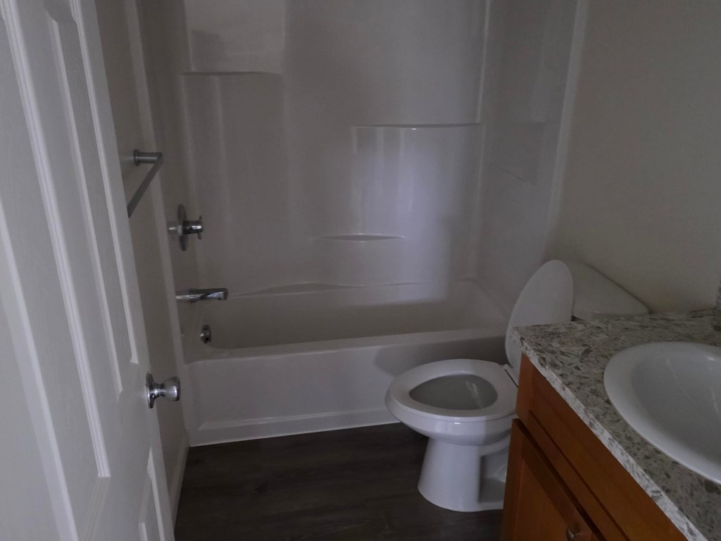 A white toilet sits next to a bathtub in a bathroom.