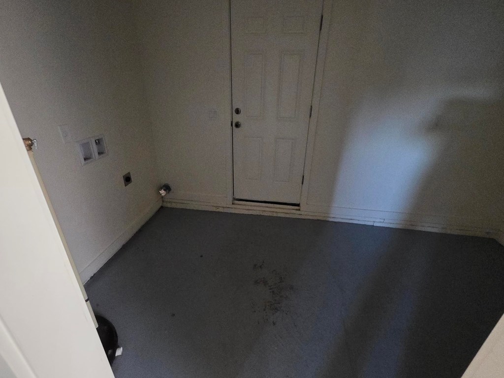 A room with a white door and a cat sitting on the floor.