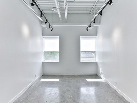 A large empty room with a concrete floor and white walls.