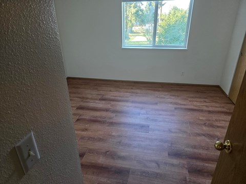 A room with a wooden floor and a window.