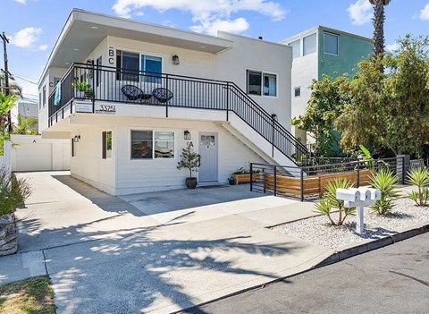 A white two-story house with a balcony on the upper floor.