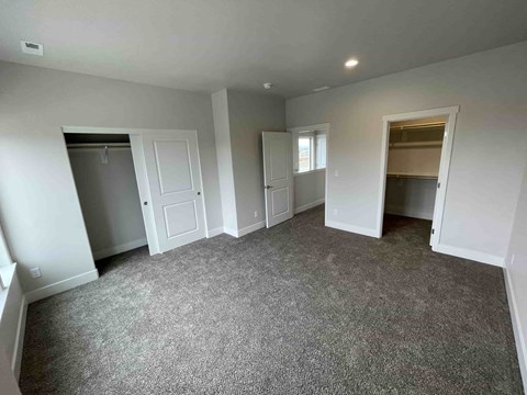 A spacious room with grey carpeting and white walls.