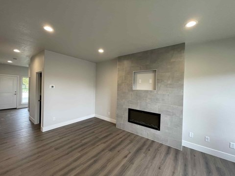 A modern living room with a fireplace and wood flooring.